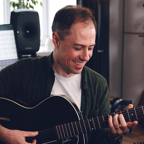 Portrait image of Bradley Kunda playing a guitar
